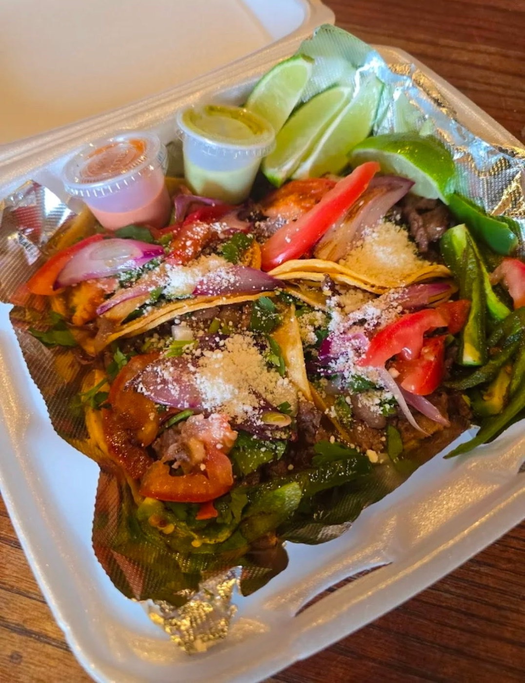 Fajita tacos with grilled onion, tomato, cilantro, cotija cheese, limes and two salsas